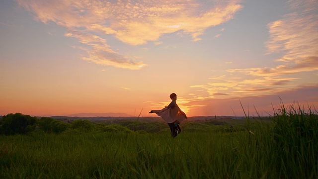 日落时分，快乐的女人在草地上纺纱视频素材