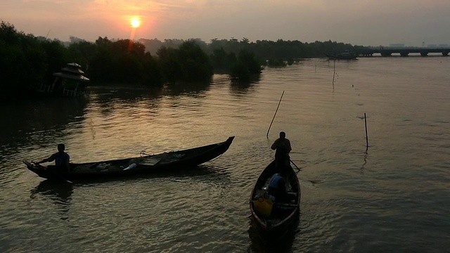 日出时，人们坐在河上两条静止的船上视频素材