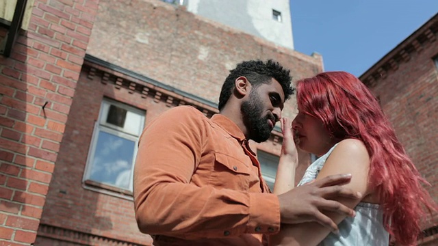 在城市的蓝天下，男人和女人在外面接吻，相互依偎视频素材