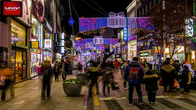 图为韩国庆尚南道釜山南浦洞圣诞树文化节上，人们在装饰着圣诞彩灯的街道上漫步视频素材