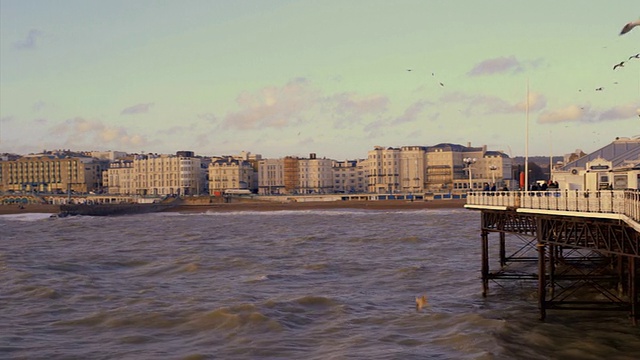 游客们在布赖顿码头附近的海滩上散步视频素材