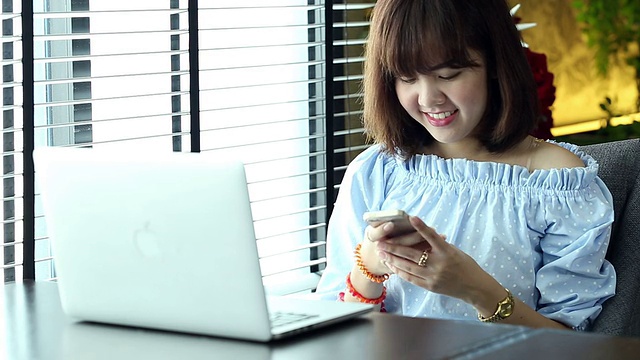 微笑的年轻女子在桌上用笔记本电脑视频素材