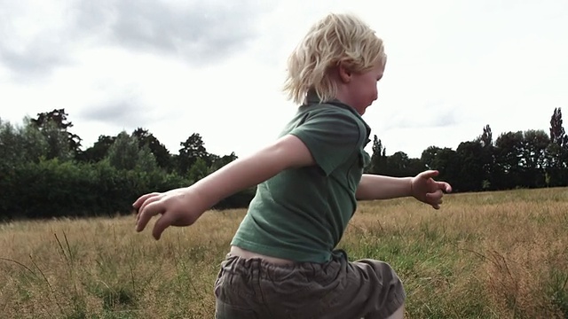 MS TS SLO MO拍摄的是一个小男孩在草地上逃离摄像机视频素材