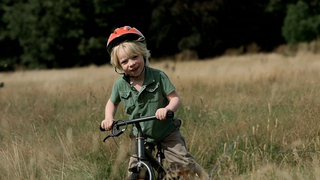 MS TS SLO MO年轻男孩骑着自行车穿过田野视频素材