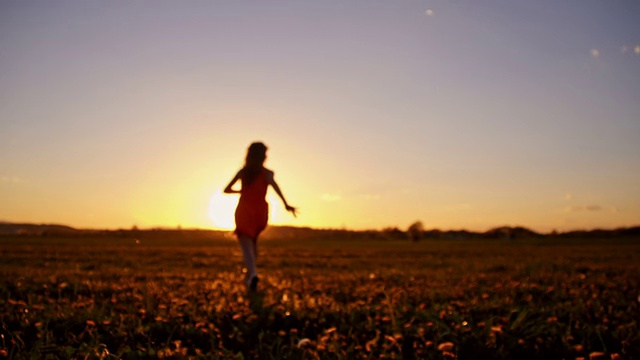 日落时分，快乐的女孩在草地上奔跑视频素材