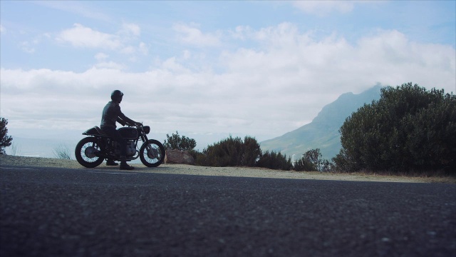 一个骑着摩托车的男人在山路上视频素材