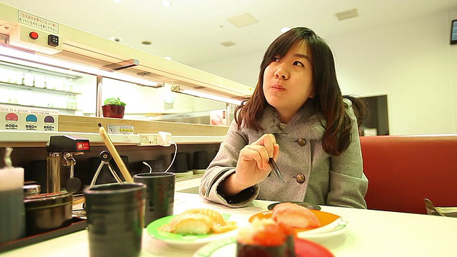 年轻美丽的亚洲女人用筷子吃寿司视频素材