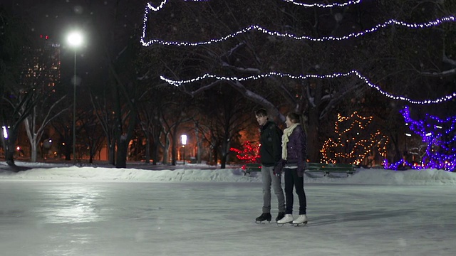 一对夫妇在一个下雪的冬天晚上有一个滑冰约会。视频下载