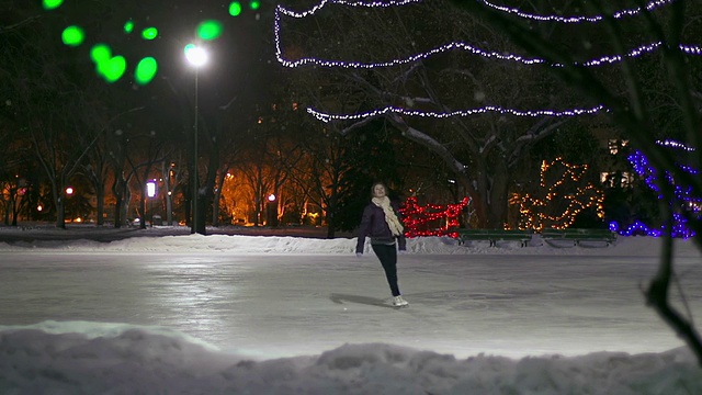 白种少女溜冰与喜悦在一个下雪的夜晚。视频下载