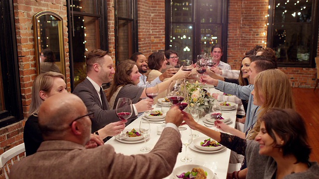 晚宴上一群朋友微笑着举杯共饮视频素材