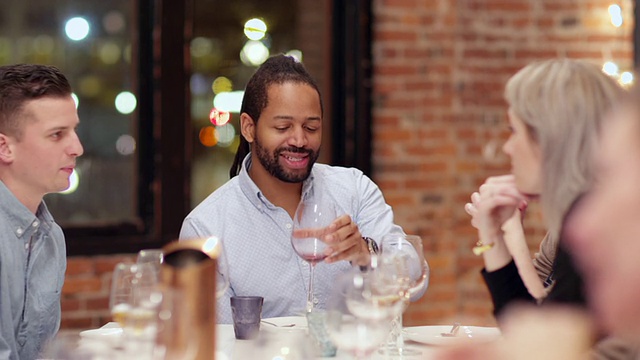 微笑的男人在晚宴上与朋友讨论喝酒视频素材