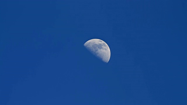 四分之一的月亮和云在蓝色的天空中移动/波利赫海滩，夏威夷考艾岛，美国视频下载