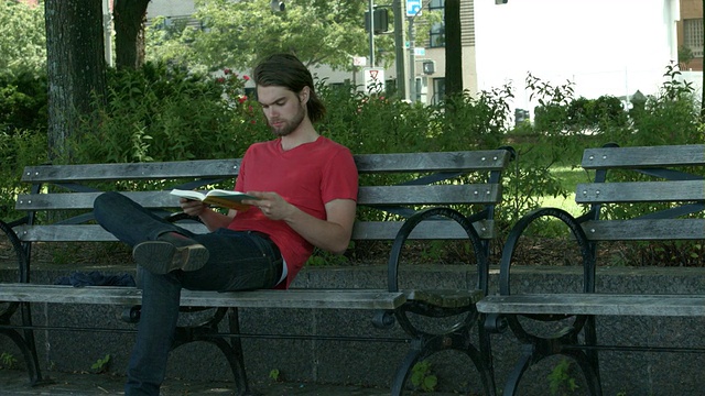 一个年轻人在纽约市的长椅上看书视频素材
