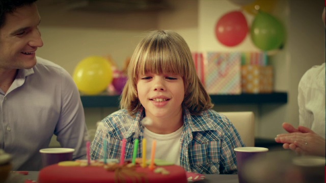 小男孩吹灭生日蛋糕上的蜡烛视频素材