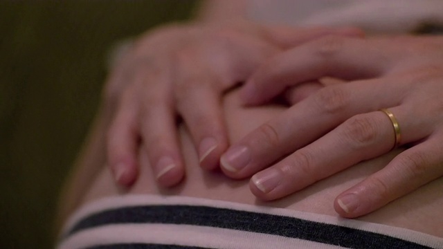 孕妇的手抚摸着自己的肚子。视频素材
