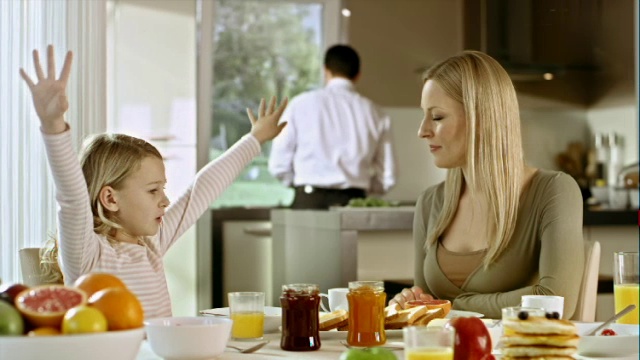 女孩在早餐桌上向她妈妈解释视频素材