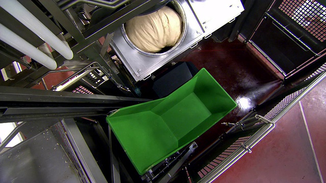面包的生面团从搅拌机里倒进面包工厂的绿色槽里视频素材