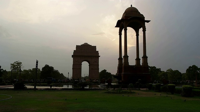 一个剪影的印度门草坪和空旷的天篷与著名的战争纪念碑印度门在背景，德里，印度视频素材