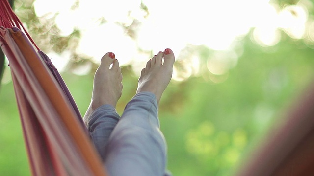 一个年轻女子在树下的吊床上休息视频素材