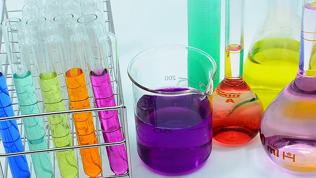 近距离摇盘:不同实验室玻璃器皿中多种颜色的化学物质视频素材