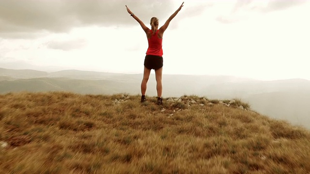 女运动员高举双手登上山顶的高空视频素材