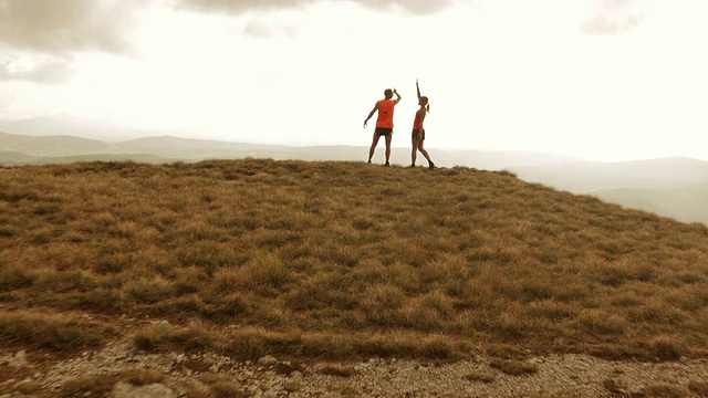 空中的跑步情侣站在山顶举手视频素材