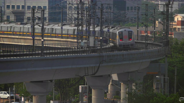 德里地铁黄线上穿过古尔冈HUDA市中心地铁站后的弯曲高架路段，背景是商业建筑视频下载