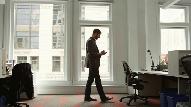 微软商人站在办公室看智能手机视频素材