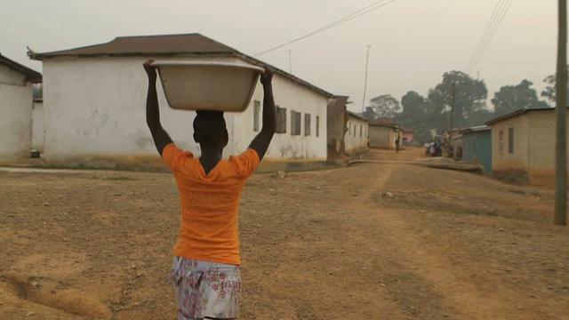在非洲的村庄里，一个年轻的女孩头顶着水视频素材