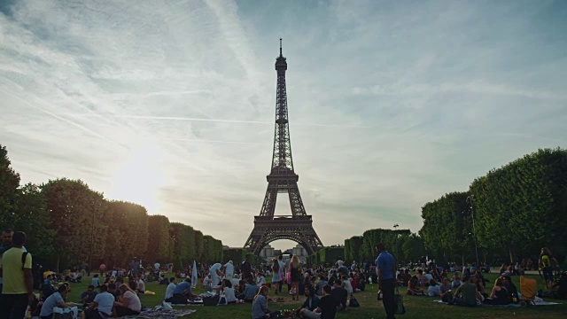 从战神广场拍摄的日落时分的埃菲尔铁塔，人们坐在草坪上视频下载
