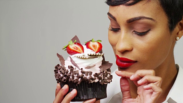 一个正在欣赏巧克力草莓纸杯蛋糕甜点的女人视频下载