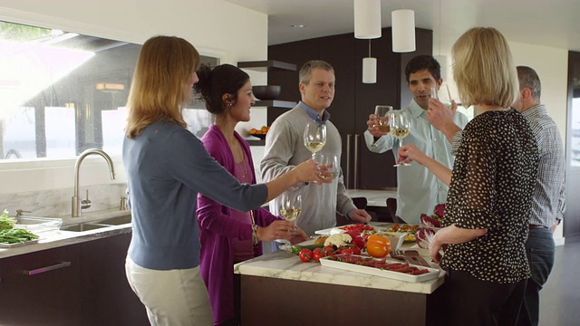 三对夫妇在晚餐前站在现代家庭的厨房里举杯互敬视频素材