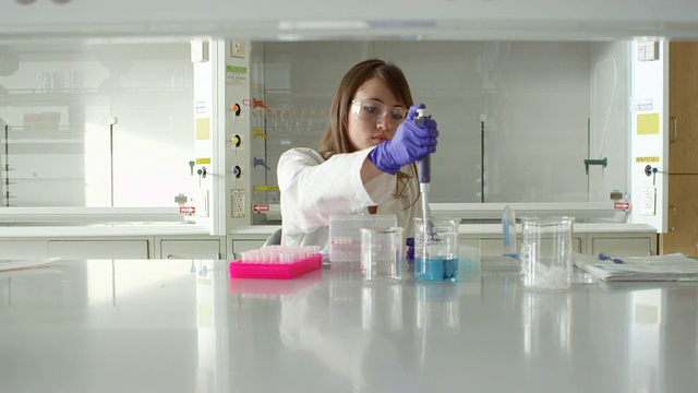 研究实验室中，女科学家用移液器将烧杯中的溶液转移到离心试管中视频素材
