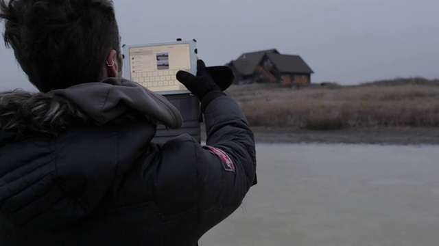 在美国蒙大拿州的乡下，一个年轻人在冬天用平板电脑拍房子。视频下载