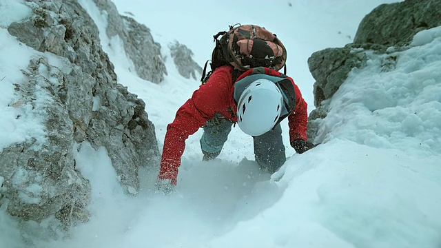 冬季登山者用斧头攀登积雪覆盖的斜坡视频下载