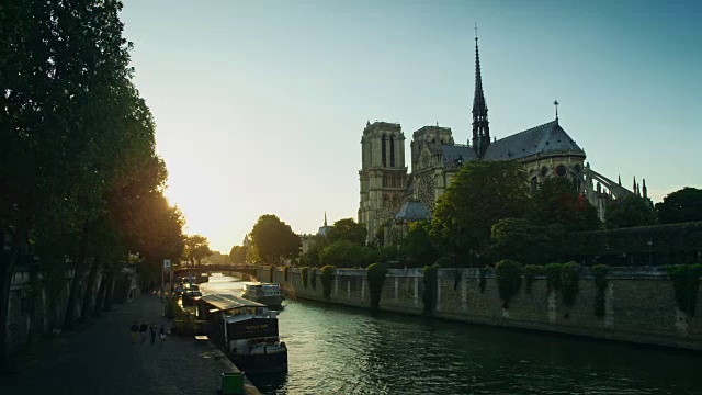 夕阳西下的巴黎圣母院和塞纳河岸边，过往的船只视频素材