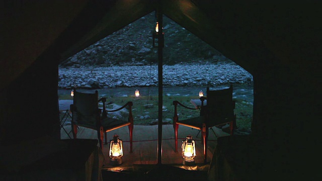 POV从内部狩猎风格的帐篷，两张椅子和两张床与灯笼和河流的背景。视频下载