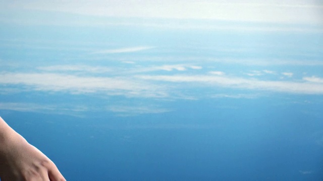 一位妇女用手在蓝天倒映的水中画出涟漪。视频素材