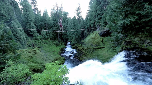人们走过森林瀑布上方的高空视频素材