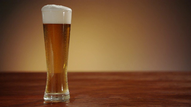 啤酒倒进玻璃杯后落在杯子里。视频素材