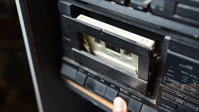 在光线暗的地方把旧卡式磁带放入录音机视频素材