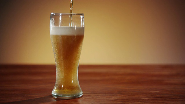 一杯琥珀色啤酒正被倒入玻璃杯中视频素材