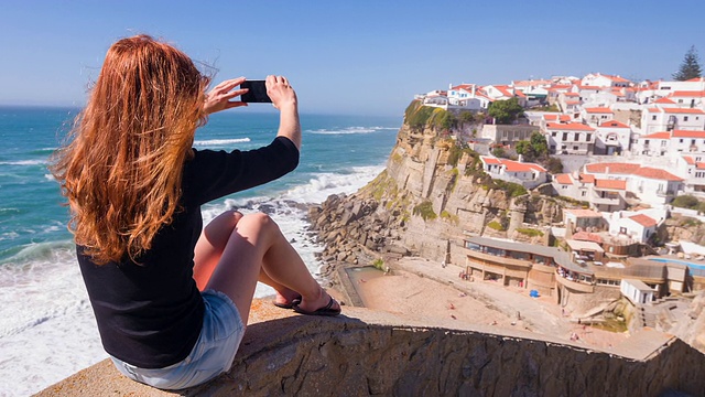 女游客在海边的悬崖上拍照视频下载