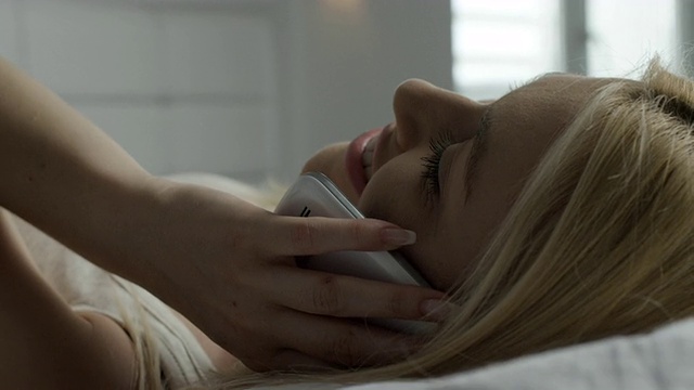 美丽的女性在床上使用电话视频下载