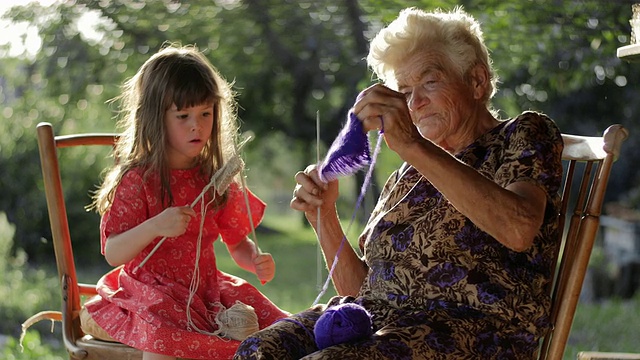一个小女孩跟着奶奶学织毛衣视频素材