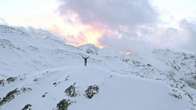 空中的冬季登山运动员胜利地把手举到山顶上视频素材