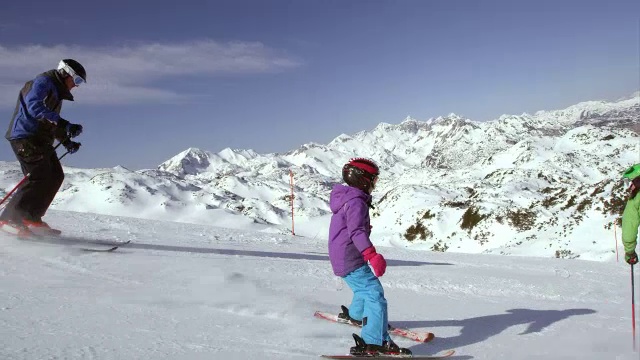 一个女孩在阳光明媚的日子和父母一起学习滑雪视频素材