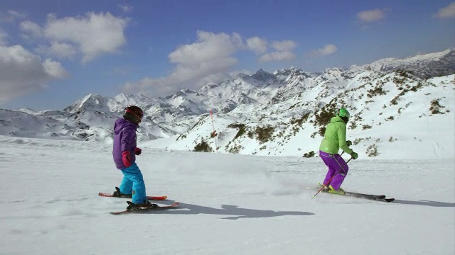 小女孩在滑雪教练后面滑雪视频素材