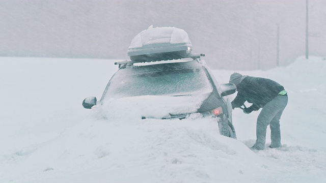 潘曼在下雪的时候把车从雪中挖出来视频素材