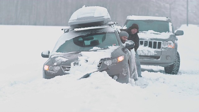 一名过路司机协助将一辆被困的汽车推出雪地视频素材